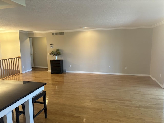 living room featuring ornamental molding, a textured ceiling, and light wood-type flooring