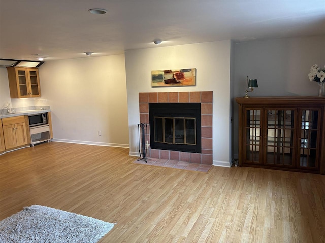 living room with a tiled fireplace, sink, and light wood-type flooring