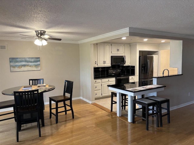 kitchen with crown molding, decorative backsplash, and black appliances