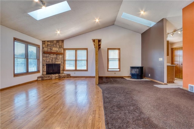 9018N Anderson Rd, Hayward, WI 54843 - unfurnished living room with a skylight, a wood stove, track lighting, lofted ceiling, and plenty of natural light