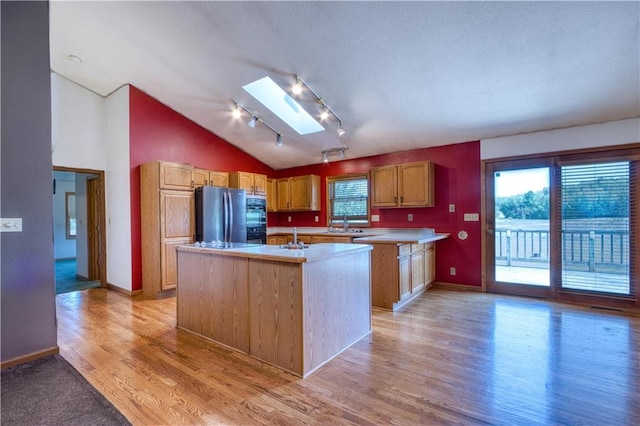 9018N Anderson Rd, Hayward, WI 54843 - kitchen featuring freestanding refrigerator, a skylight, light wood finished floors, light countertops, and a kitchen island with sink