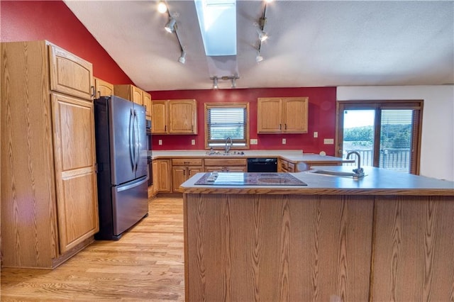 kitchen with black appliances, sink, light hardwood / wood-style floors, vaulted ceiling, and track lighting