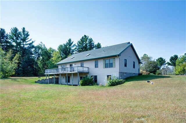 rear view of property with a wooden deck and a yard