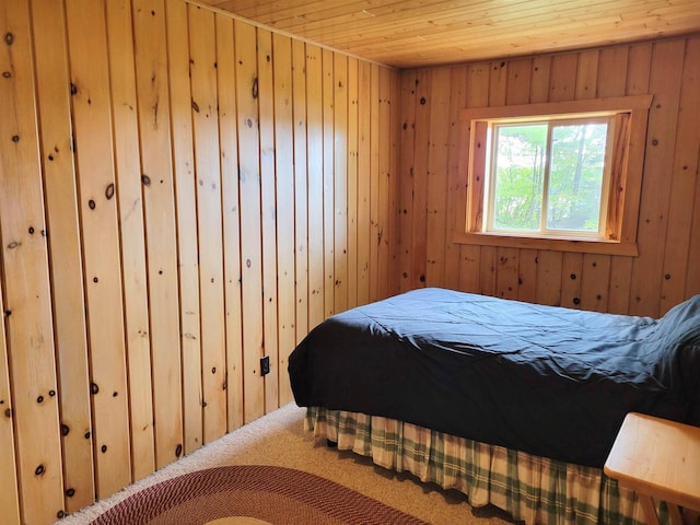 bedroom with wooden ceiling, wooden walls, and carpet