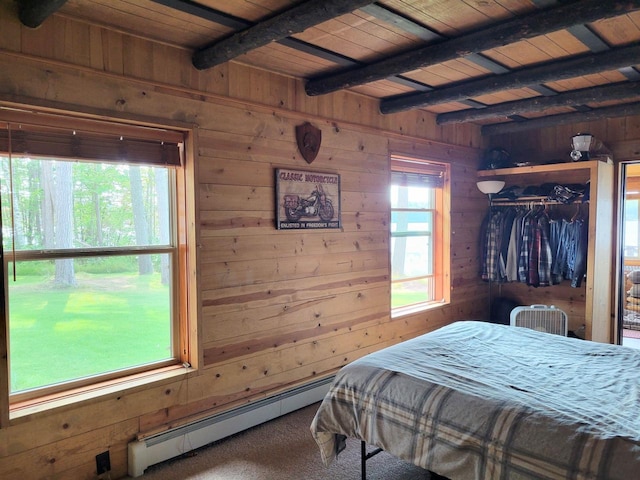 bedroom with a baseboard heating unit, wooden walls, and carpet