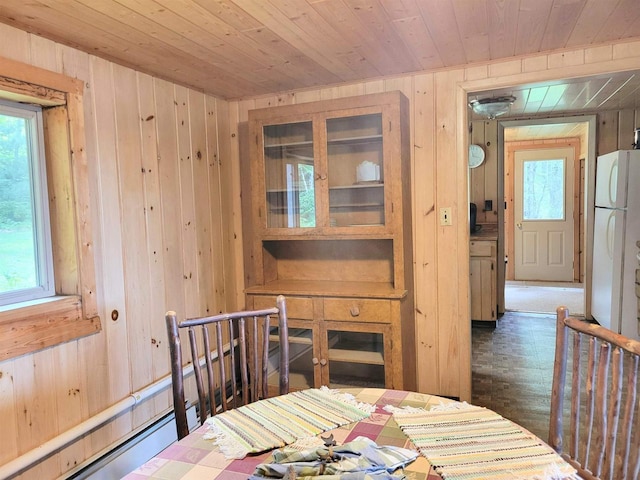 dining area with a baseboard heating unit, wood ceiling, plenty of natural light, and wooden walls