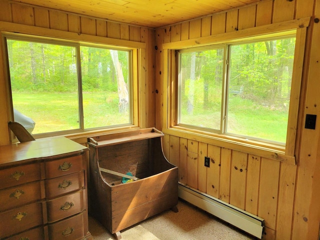 interior space with a baseboard heating unit, light colored carpet, wooden walls, and wooden ceiling