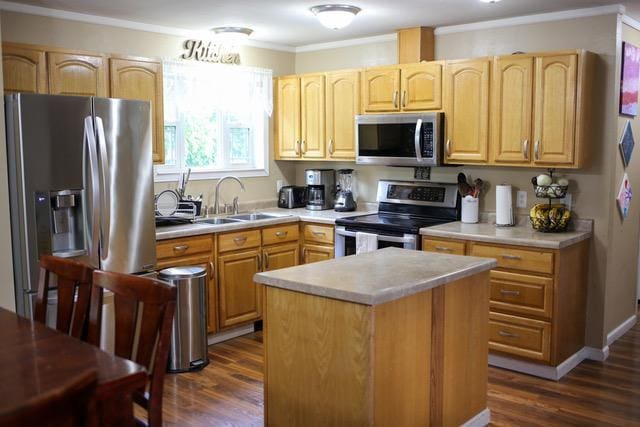 kitchen with ornamental molding, sink, a center island, dark wood-type flooring, and appliances with stainless steel finishes