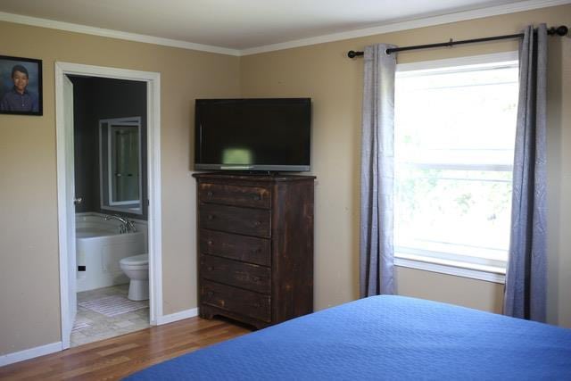 bedroom featuring hardwood / wood-style floors, crown molding, and ensuite bath