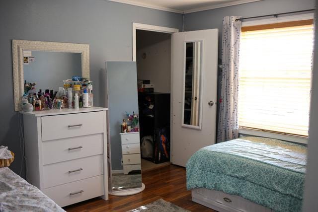 bedroom with ornamental molding and dark wood-type flooring