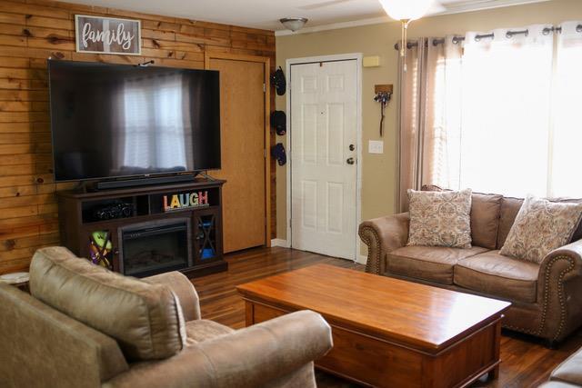 living room featuring a wealth of natural light, dark wood-type flooring, and wooden walls