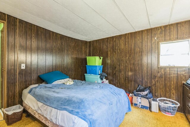 bedroom featuring carpet flooring and wooden walls