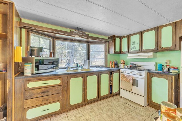 kitchen featuring a textured ceiling, white range with gas stovetop, and sink