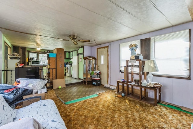 interior space with ceiling fan, wooden walls, and a healthy amount of sunlight