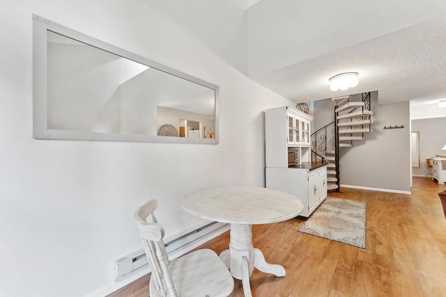 dining room featuring a textured ceiling, light hardwood / wood-style flooring, and a baseboard radiator