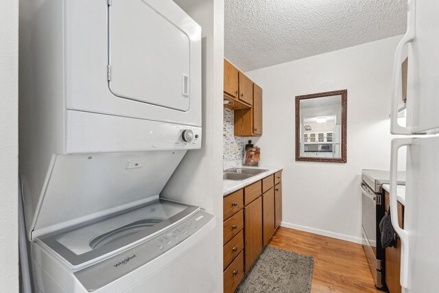 interior space featuring a textured ceiling, light wood-type flooring, sink, and stacked washer and dryer