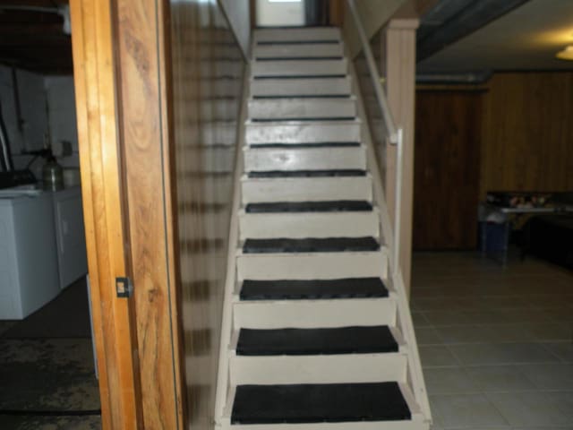 stairs with wood walls and tile patterned floors