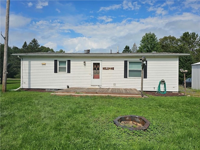 rear view of property with a yard and an outdoor fire pit