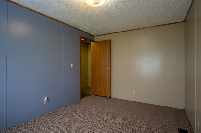 spare room featuring a textured ceiling, ornamental molding, and carpet floors