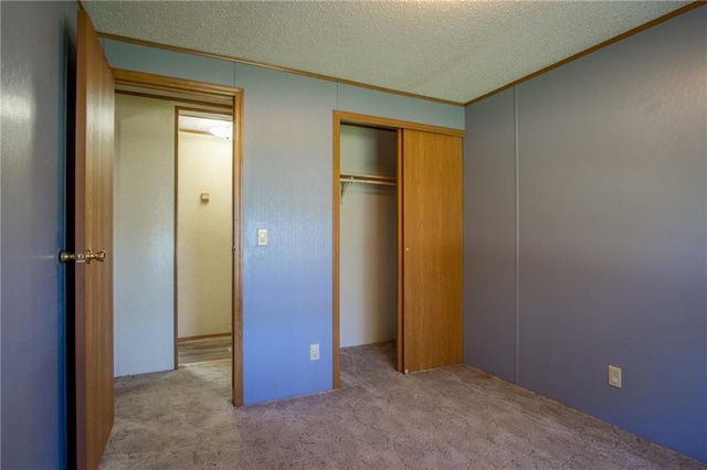 unfurnished bedroom with ornamental molding, a closet, a textured ceiling, and light colored carpet