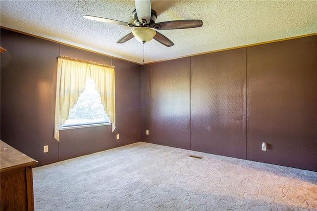 carpeted spare room featuring ceiling fan and a textured ceiling