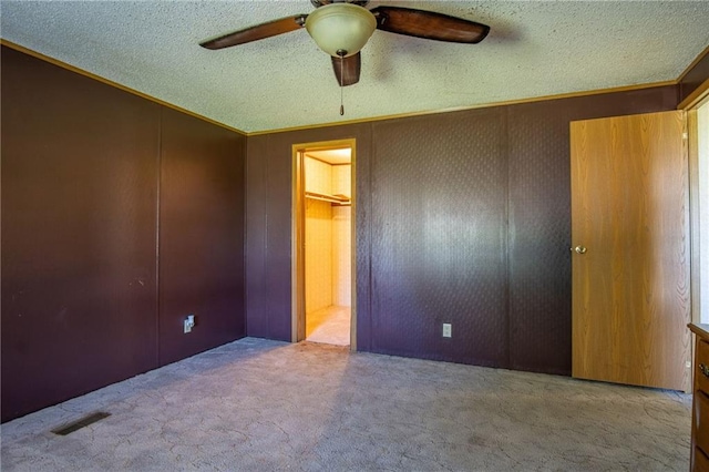 unfurnished bedroom featuring ceiling fan, light colored carpet, a textured ceiling, and a closet