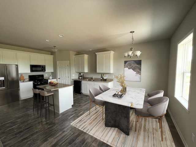 dining room featuring dark hardwood / wood-style flooring, a wealth of natural light, a notable chandelier, and sink