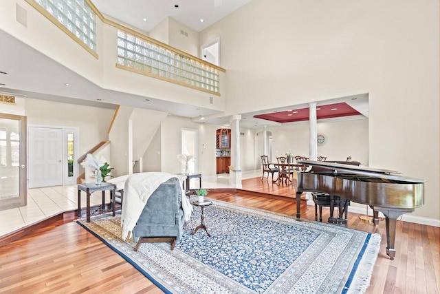 living room with a high ceiling, decorative columns, and hardwood / wood-style flooring