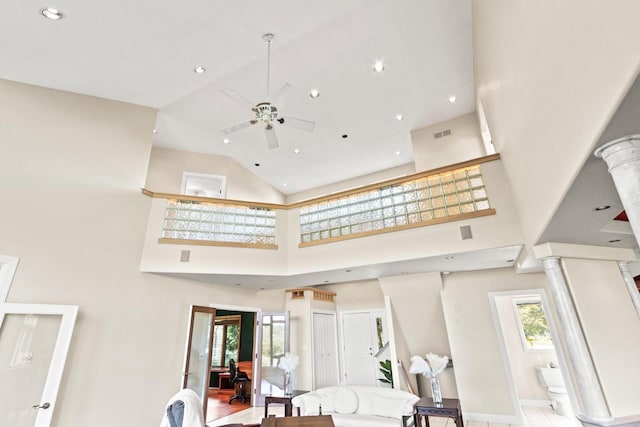 interior space featuring ceiling fan, hardwood / wood-style flooring, decorative columns, and high vaulted ceiling