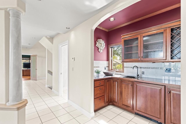 kitchen featuring crown molding, decorative columns, sink, and tasteful backsplash