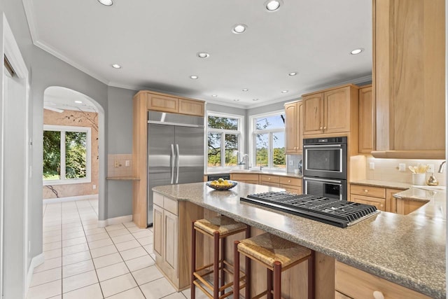 kitchen featuring a breakfast bar, decorative backsplash, appliances with stainless steel finishes, light tile patterned floors, and ornamental molding