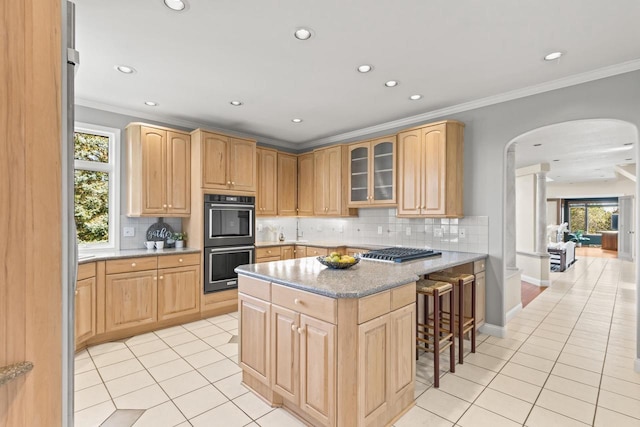 kitchen featuring appliances with stainless steel finishes, a healthy amount of sunlight, a kitchen bar, and decorative backsplash