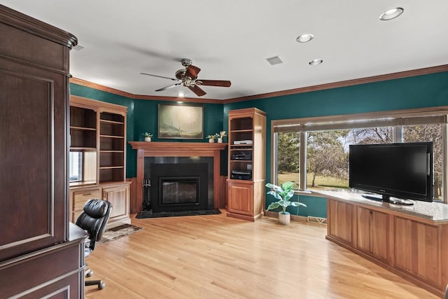 office with built in desk, ornamental molding, ceiling fan, and light hardwood / wood-style flooring