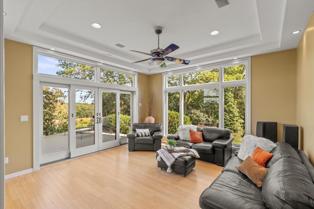 living room featuring a raised ceiling, ceiling fan, french doors, and light hardwood / wood-style flooring