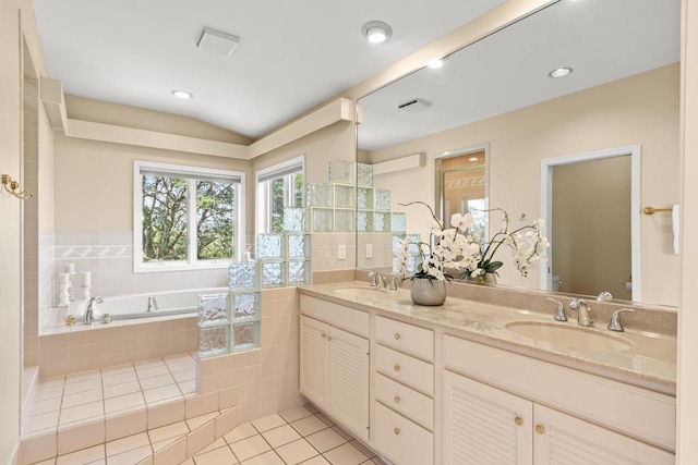 bathroom with vanity, lofted ceiling, toilet, a relaxing tiled tub, and tile patterned flooring