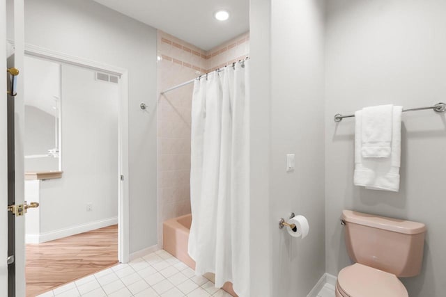 bathroom featuring wood-type flooring, shower / bathtub combination with curtain, and toilet