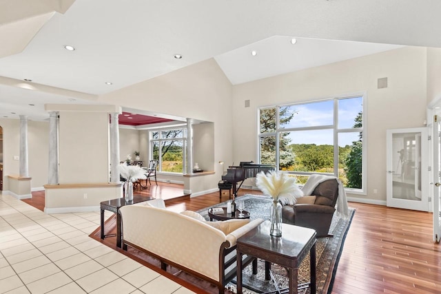 living room with high vaulted ceiling, decorative columns, and light hardwood / wood-style floors