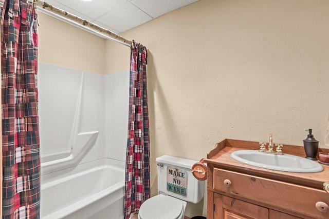 full bathroom featuring shower / tub combo, a drop ceiling, vanity, and toilet