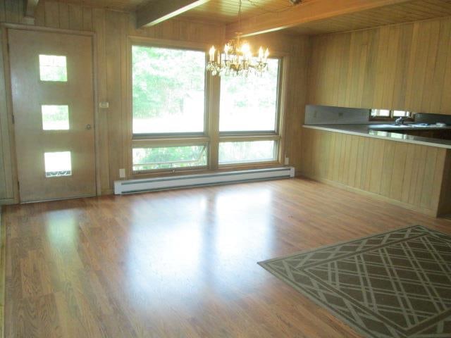 interior space featuring a baseboard heating unit, a wealth of natural light, beamed ceiling, and hardwood / wood-style flooring