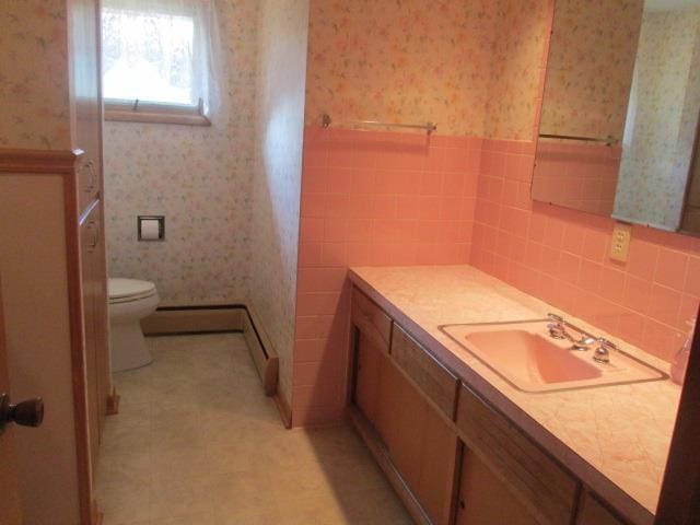 bathroom featuring vanity, toilet, baseboard heating, and decorative backsplash