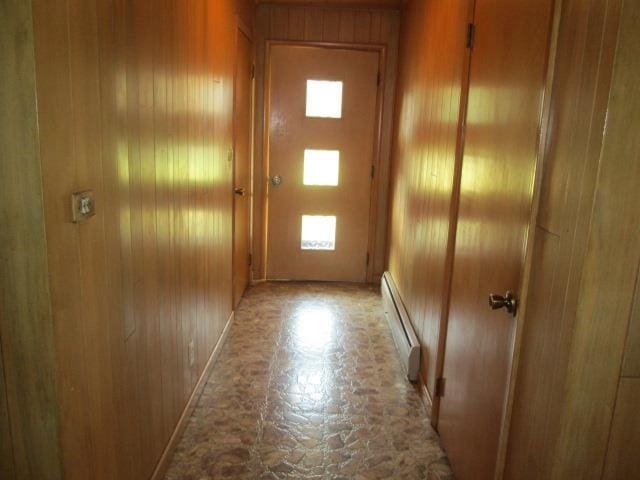 doorway featuring a baseboard radiator and wood walls