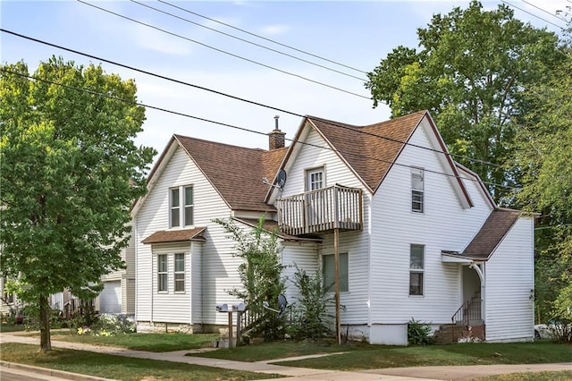 view of front of property with a balcony, a garage, and a front lawn