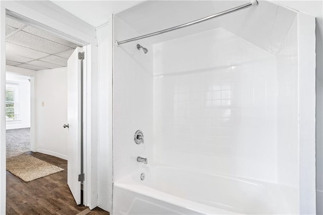 bathroom with wood-type flooring, a drop ceiling, and shower / bath combination