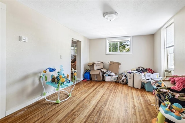 playroom featuring baseboards, wood finished floors, and a textured ceiling