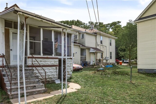 rear view of property with a sunroom and a yard