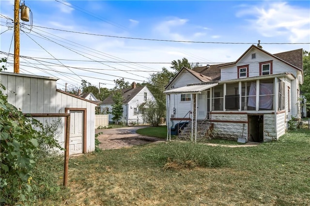 back of house featuring a lawn and a sunroom