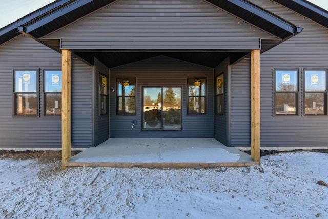 snow covered property entrance with a patio area