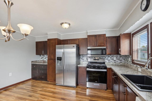 kitchen featuring appliances with stainless steel finishes, light wood-type flooring, sink, and tasteful backsplash