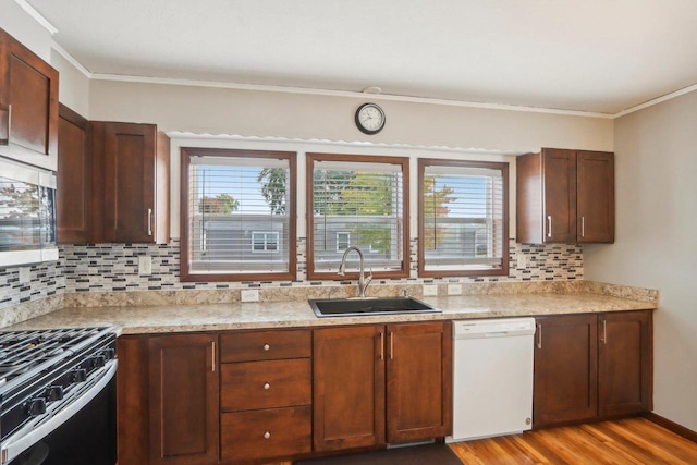 kitchen featuring tasteful backsplash, sink, ornamental molding, light hardwood / wood-style flooring, and appliances with stainless steel finishes