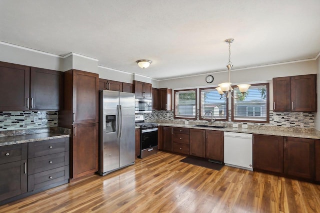 kitchen featuring tasteful backsplash, sink, hanging light fixtures, light hardwood / wood-style flooring, and appliances with stainless steel finishes